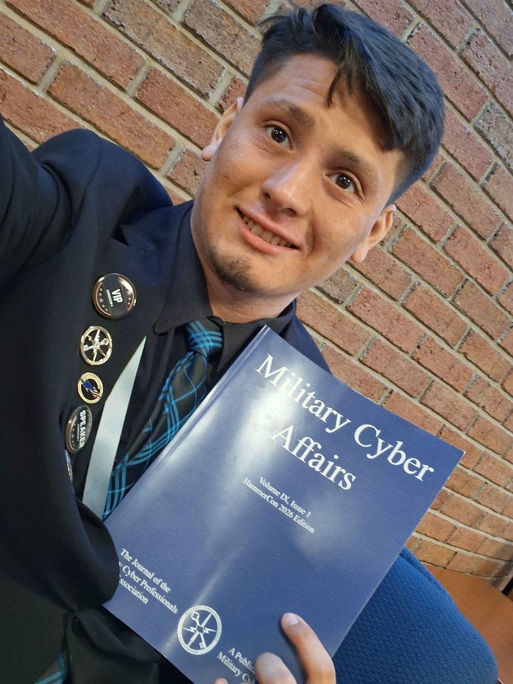 Adrian holding a printed copy of the journal Military Cyber Affairs
